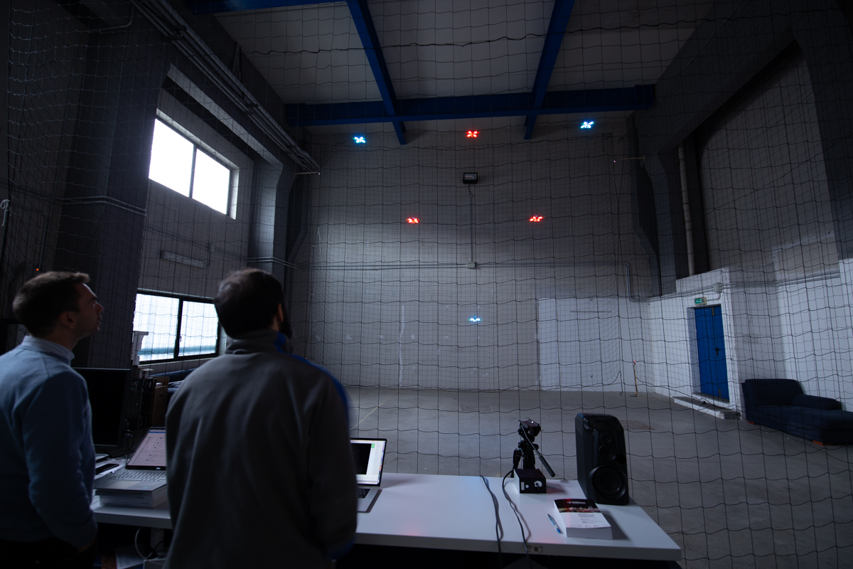 Indoor drone test flight with colored drones in a warehouse space