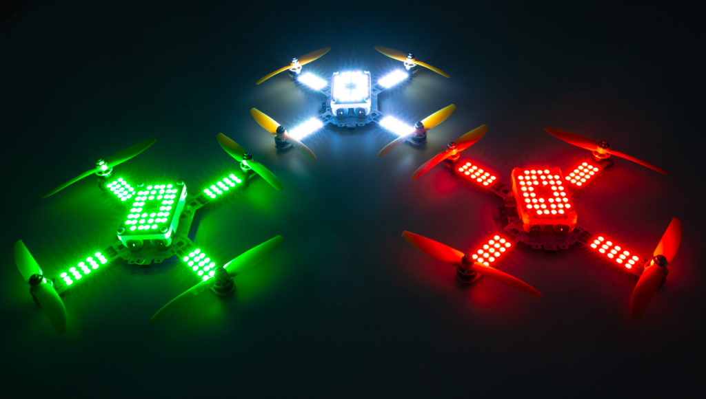 Three LuminousBee drones glowing green, white and red against a dark background