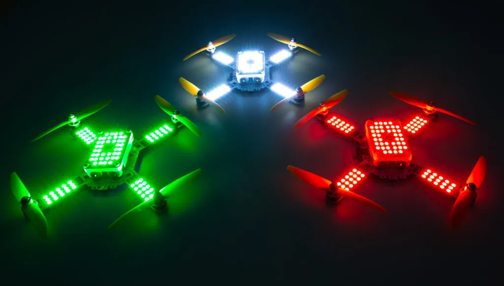 Three LuminousBee drones glowing green, white and red against a dark background