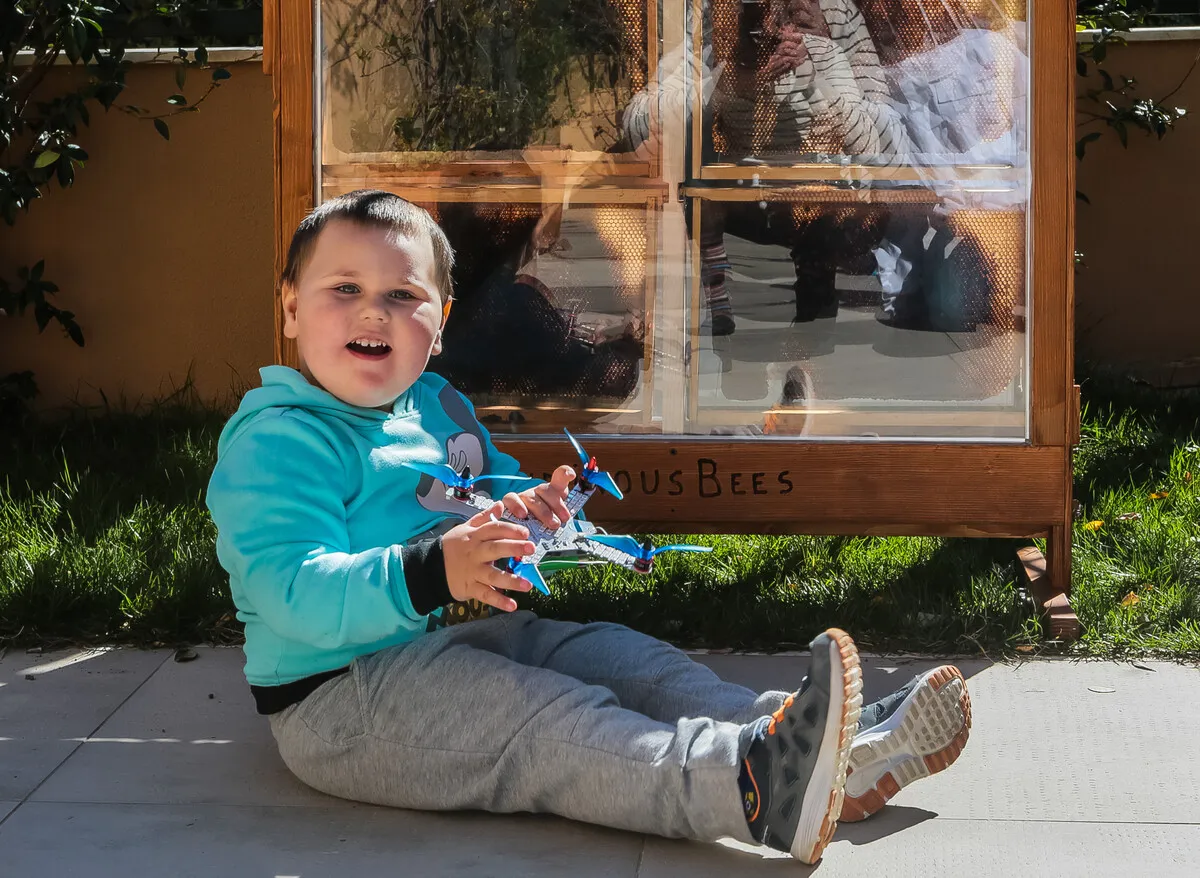 Child with drone in front of transparent beehive installation